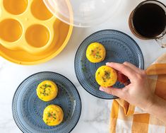 two plates with mini muffins on them next to a cup of coffee and an orange towel