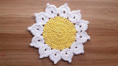 a yellow and white crocheted doily sitting on top of a wooden table