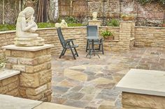 a patio with chairs and a statue in the center, surrounded by brick walls that have been built into it