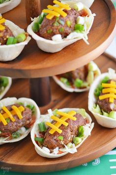 small appetizers with cheese on them are arranged on a wooden platter, ready to be eaten