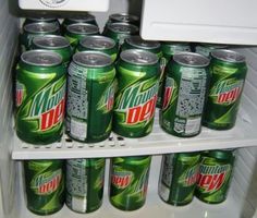 several cans of mountain dew sit in an open refrigerator