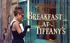 a woman walking past a window with the words in breakfast at tiffany's