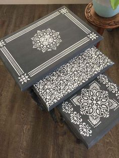 three black and white tables with designs on them sitting on top of a wooden floor