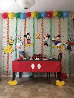 a mickey mouse themed birthday party with balloons and streamers on the wall, along with decorations