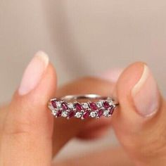 a woman's hand holding a diamond and ruby ring