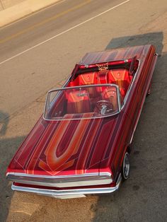 an old red car is parked on the side of the road with its hood up