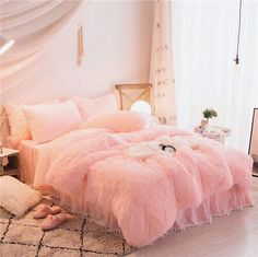 a bed with pink fluffy sheets and pillows