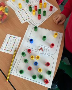 two children are playing with matching objects on the table in front of them, and one child is holding a pencil