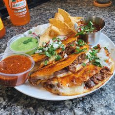 a white plate topped with tacos and tortillas next to guacamole