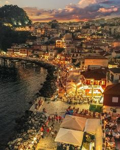 an aerial view of a city at night with people sitting and standing on the beach