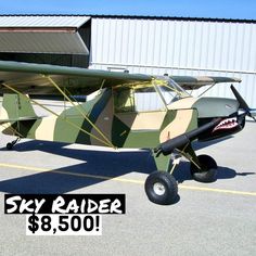 an old style airplane is parked in front of a building with the sky raider $ 8, 500