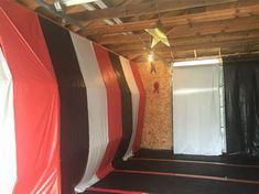 an unfinished room with red, white and black curtains