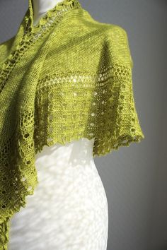 a knitted shawl is shown on a mannequin