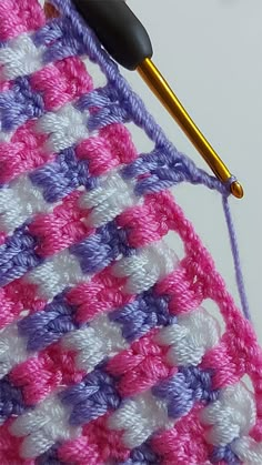 the crochet pattern is being worked on with a knitting needle and yarn ball