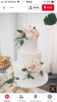 a white wedding cake with flowers and cookies on the table next to other desserts