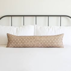 a white bed topped with pillows and a black metal headboard next to a wall