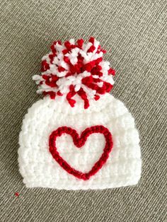 a crocheted white hat with a red heart on the front and bottom part