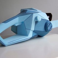 an origami paper model of a blue object on a white counter top with one eye open