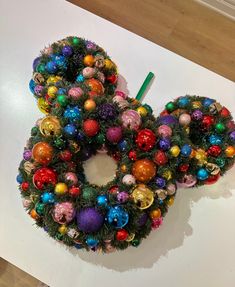 a mickey mouse christmas wreath with ornaments on the front and side, sitting on a table