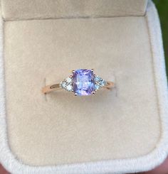 an engagement ring with a tan and blue stone surrounded by three diamonds in a box