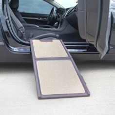 the interior of a car with its door open and carpet on the ground next to it