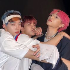 three young men with pink hair are posing for the camera, one is holding his arm around another man's shoulder