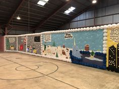 an indoor basketball court decorated for christmas with holiday decorations on the wall and around it