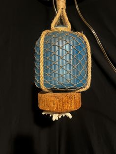 a blue object hanging from a rope on a black background