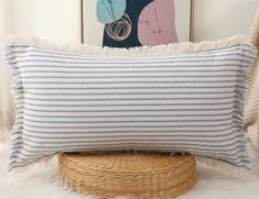 a blue and white striped pillow sitting on top of a bed next to a basket