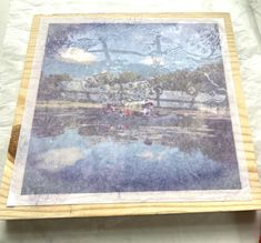 a wooden frame with a painting on it sitting on top of a white tablecloth