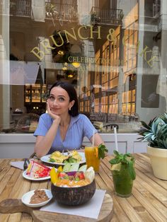 a woman sitting at a table in front of a glass window with food on it