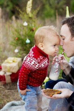 a man holding a baby in his lap and kissing him on the cheek, while he is