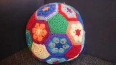 a multicolored crocheted ball sitting on top of a black chair next to a wall