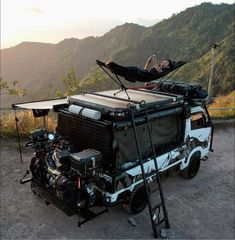 a man laying in a hammock on top of a vehicle with an engine