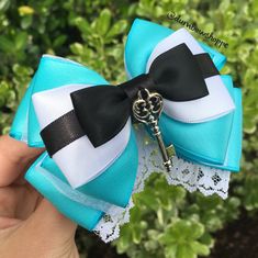 a hand holding a blue and white bow with a skeleton key on it