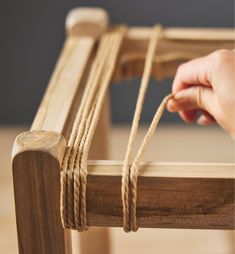 a person is pulling rope from a wooden bench with one hand and another hand on the edge