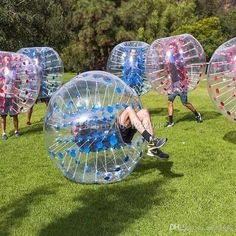 several people are playing with large inflatable balls on the grass, and one person is laying down