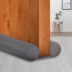 the corner of a room with a wooden door and grey pipe on the floor next to it