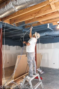 a man standing on a ladder working on the ceiling