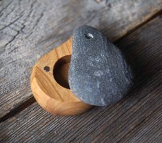 two rocks in a wooden holder on top of a wood table, one is black and the other is gray