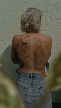 the back of a woman's body with tattoos on it