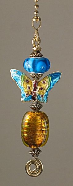 a glass butterfly hanging from a chain with a bead on it's end