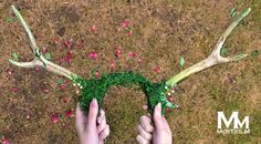 two hands are holding fake antlers made out of green grass and pink confetti