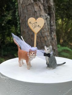 a cake topper with two cats and a cat angel holding a wooden sign that says mr & mrs