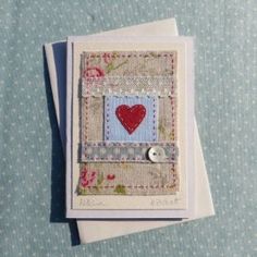 a card with a red heart on it sitting on top of a blue tablecloth