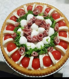 a pizza with tomatoes, mozzarella and other toppings on it sitting on a table