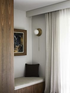 a bedroom with a window seat next to a painting on the wall and drapes