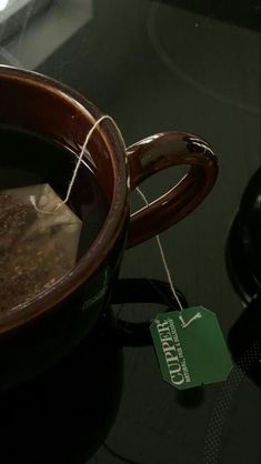 there is a cup of coffee on the table with a tag hanging from it's handle