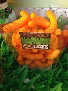 some carrots are in a clear bowl on the grass, and there is a sign that says carrots