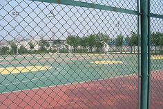 the tennis court is fenced off and ready to play